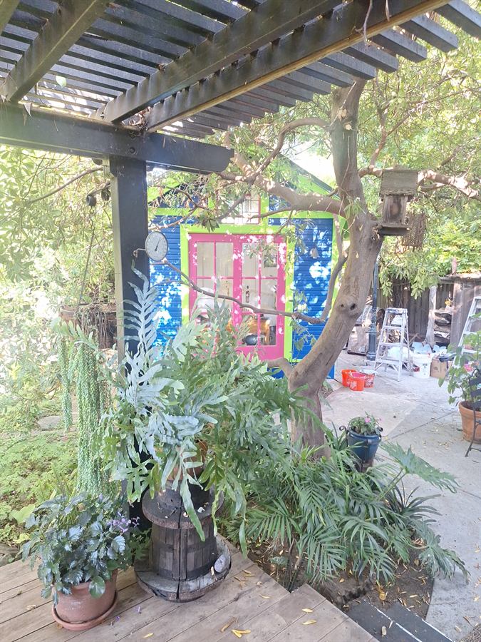 Repainted cottage framed by a pergola and garden planting