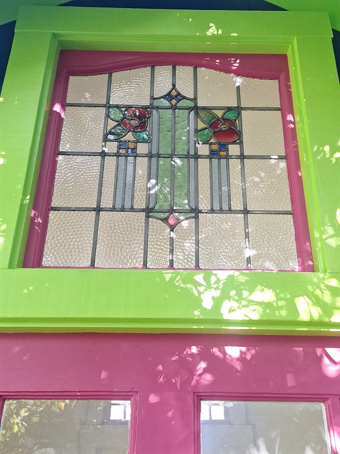Restored stained glass transom window set in a freshly painted lime and magenta frame